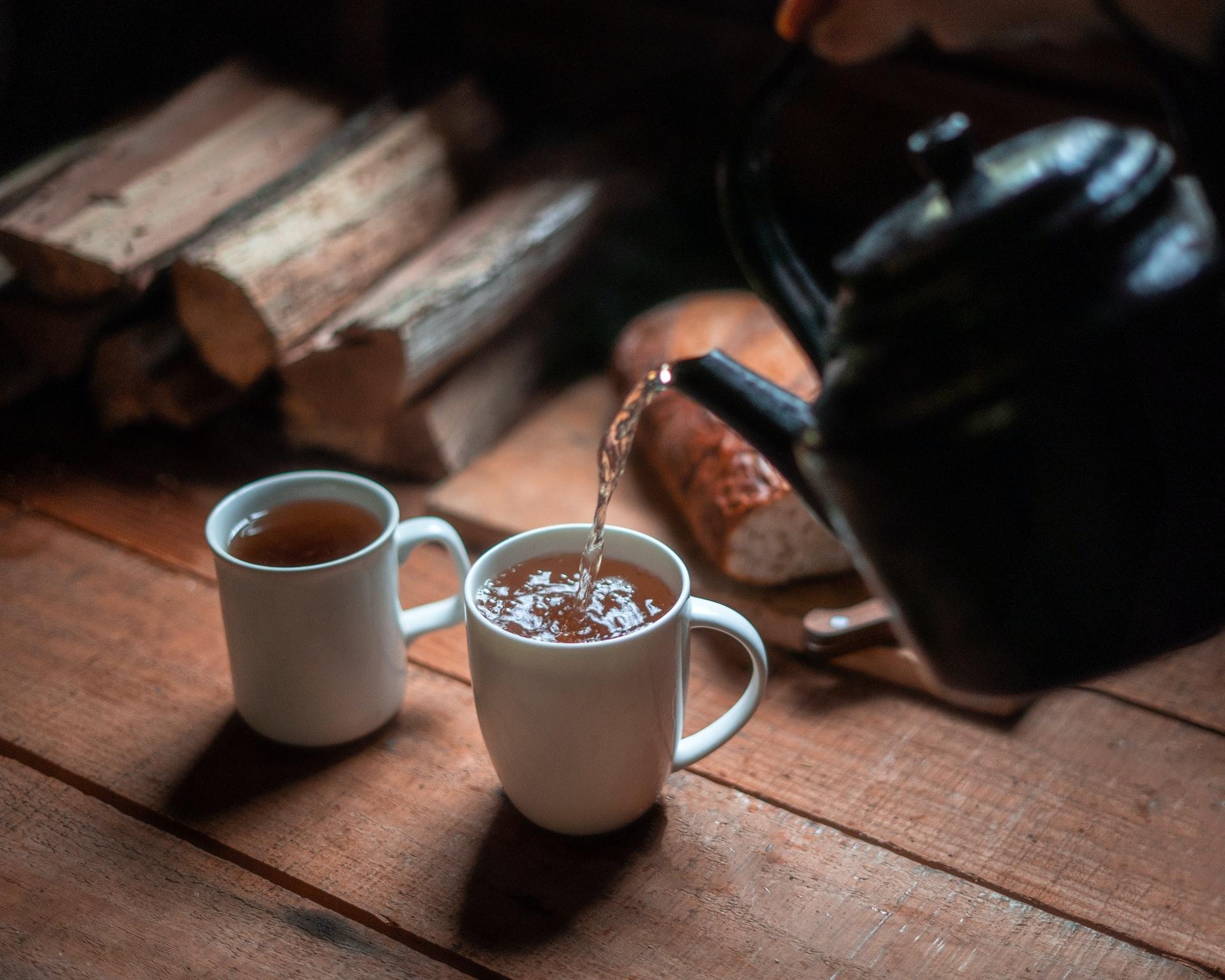 Pouring clean water from kettle into cup of tea