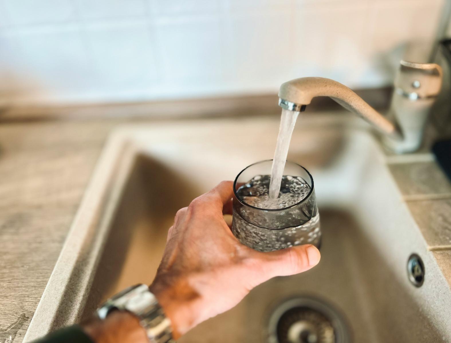 A man getting drinking water from a tap