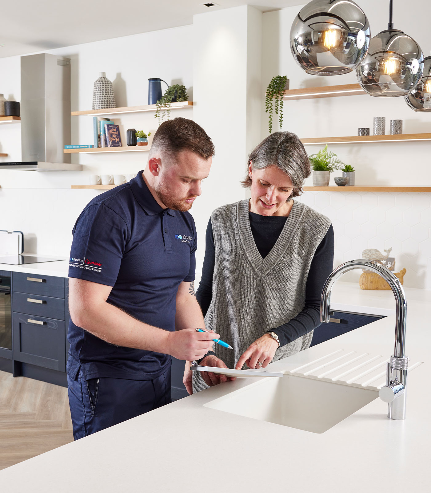 Kinetico engineer discussing water treatment with a customer in her kitchen