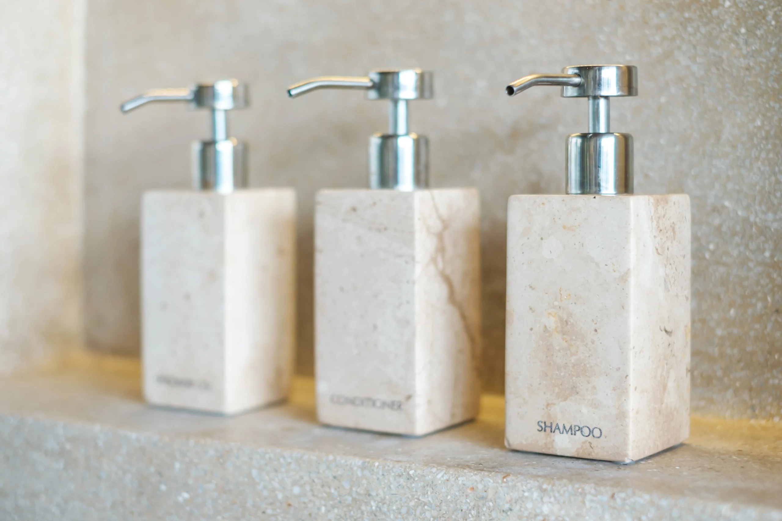 Shampoo and conditioner dispensers on a bathroom shelf